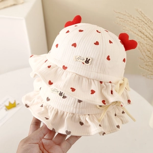 Cream baby bucket hat with red heart print, lace-up strap and ruffled brim for autumn