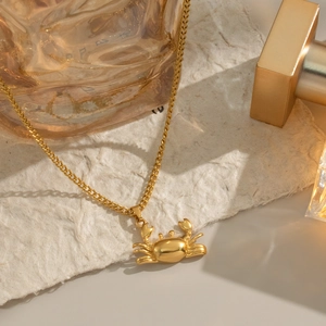 Gros plan détaillé du collier avec pendentif crabe plaqué or 18 carats sur papier gaufré