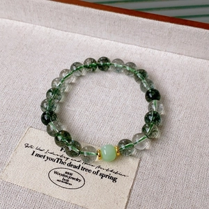 Detail view of transparent green phantom crystal beads and gold spacer on hemp fabric