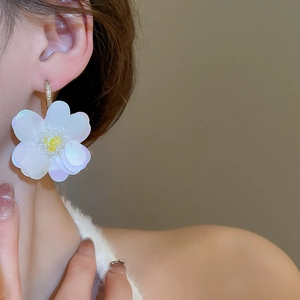 Macro shot of large iridescent white sequin flower earring on model for luxury style