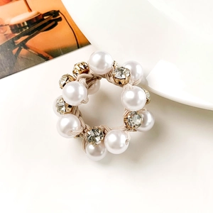 Close-up of elegant pearl hair tie with rhinestones on a minimalist white background