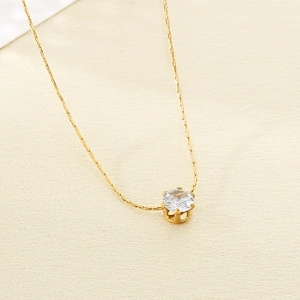 Détail d'un collier doré orné d'un zircon blanc brillant avec serti à 6 griffes