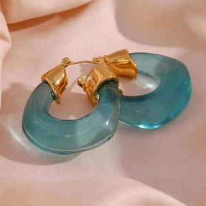 Detailed macro view of U-shaped green acrylic hoop earrings with a gold metal clasp