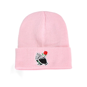 Pink knit beanie with embroidered praying hands and rose on a clean white background