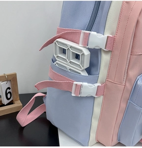 Detail view of the side pocket with adjustable pink buckles on a color-block backpack
