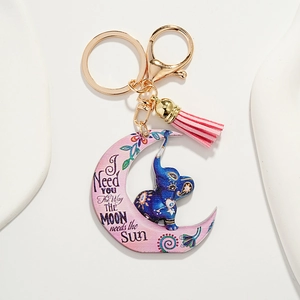 Macro detail of crescent moon keychain with pink tassel and blue elephant totem design