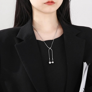 Detail showing an adjustable silver snake chain necklace with U-shaped sphere pendant on model