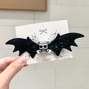 Halloween bat hair clip featuring a white skull and crossbones with silver spiderweb patterns