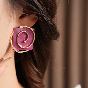 Detail of vintage square purple enamel clip earrings with golden spiral on model