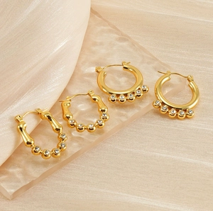 Detailed macro view of 18K gold plated pearl hoop earrings on champagne silk fabric