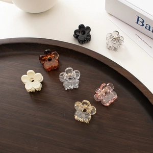 Mini floral hair claws in assorted colors like amber and black on a wooden tray