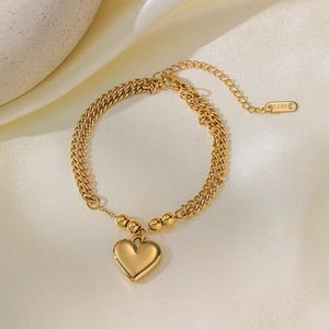 Golden stainless steel double layer heart pendant bracelet on white silk texture