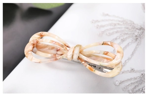 Close-up of cream bow hair clip with tortoiseshell texture and silver metal base