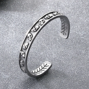Détail macro du bracelet manchette gothique argenté avec crânes et gravures punk