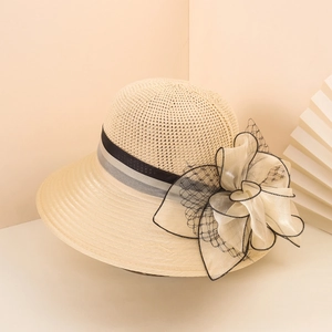 Detail view of straw sun hat featuring a large mesh bow and breathable woven texture