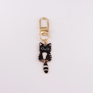 Detail of a mini alloy cat keychain with black and white stripes and golden clasp