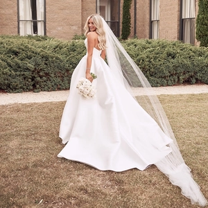 Elegant strapless satin bridal gown with high slit and long rhinestone-studded veil