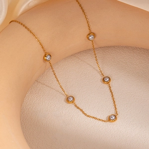 Detailed shot of golden thin chain necklace with five grey beads on art plaster pedestal