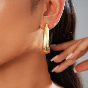Close-up of a polished gold teardrop earring showcasing smooth mirror finish and curve