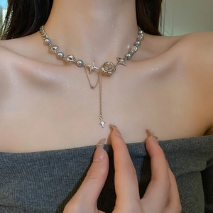 Close-up of silver necklace with grey pearl, star charms and long chain tassels on a model