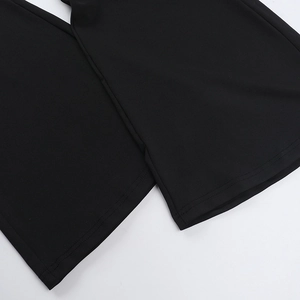 Close-up of double-stitched hem and elastic knit fabric on black street style trousers