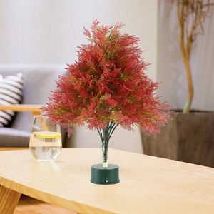 Close-up of mini red pine needle Christmas tree with black round base for tabletop decor