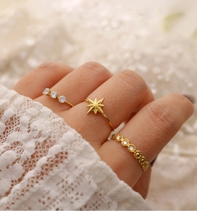 Detailed view of three gold-plated stainless steel star and diamond rings on model hand