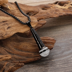 Close-up of black microphone pendant with sparkling rhinestones on dark wood background
