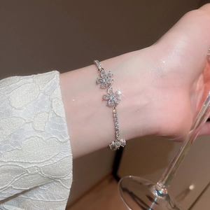 Detail of silver flower bracelet with zircon stones on wrist with lace sleeve