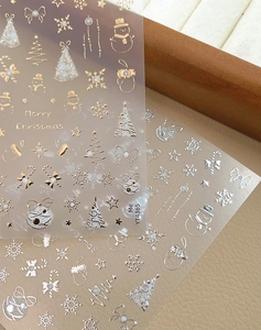 Macro detail of metallic gold and silver Christmas nail stickers with snowflakes and bows