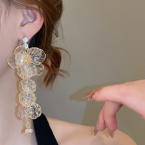 Close-up of model wearing long acrylic flower tassel earrings with sparkling rhinestone details