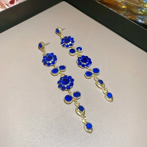 Macro shot of gold tassel earrings with dark blue gems and floral vintage elements