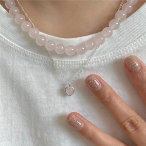 Detail of layered pink crystal bead necklace and heart pendant on silver chain
