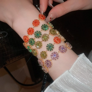 Macro detail of 18k gold plated bracelet featuring colorful zircon flower pendants on wrist