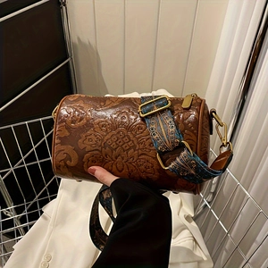 Detail of brown barrel bag featuring floral embossing and ethnic embroidered strap