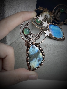 Macro detail of handmade bronze wire wrapped labradorite pendant with moon and star design