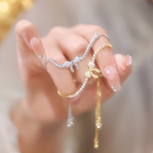 Macro shot of silver and gold bow bracelets with pavé zircons on a hand