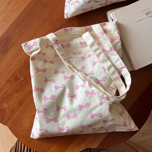 Détail d'un sac cabas en toile avec nœuds roses et pois bleus sur table en bois