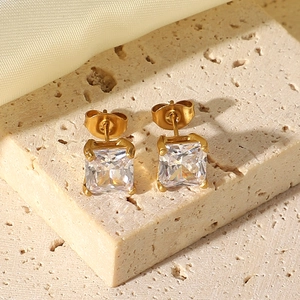 Macro shot of 18K gold-plated earrings with square zircon on textured stone base