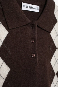 Detail of the argyle knit polo collar with resin buttons and textured fabric