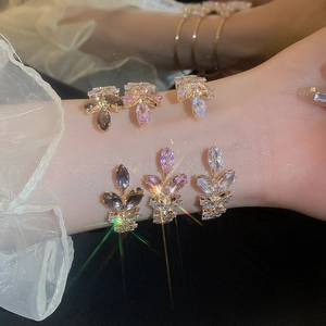 Elegant gold leaf open bracelet set with marquise cut purple and white crystals on a hand