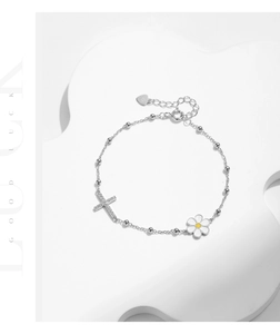 Macro detail of s925 silver bracelet showing daisy charm, cross and metal hallmark