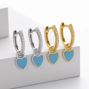 Detail of silver and gold heart hoop earrings with blue enamel and sparkling pavé stones