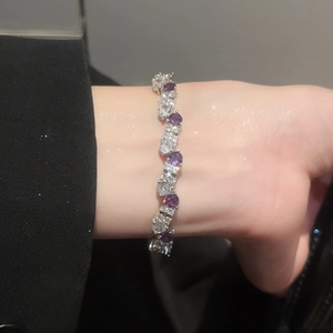 Detailed view of wavy silver bracelet with purple and white round-cut zircons on wrist
