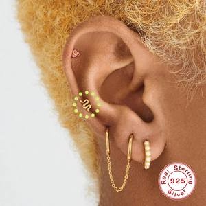 Close-up of S925 sterling silver gold ear studs with snake and ruby design on model ear