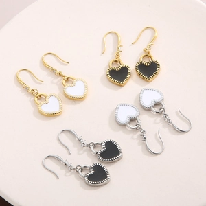 Detail of heart stud earrings in gold and silver finishes with black and white enamel