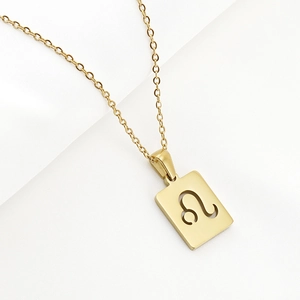 Macro shot of 18K gold Leo zodiac pendant with hollow square design on white fabric