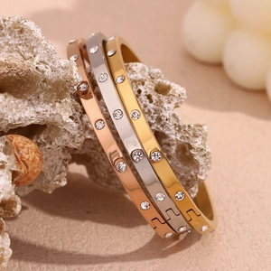 Detailed view of gold, silver, and rose gold hinged bangles with cubic zirconia on stones