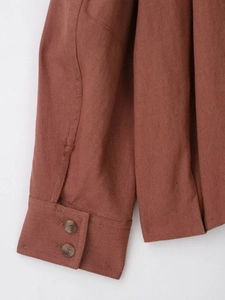 Detailed close-up of double-button cuffs and stitching on a brown suede jacket