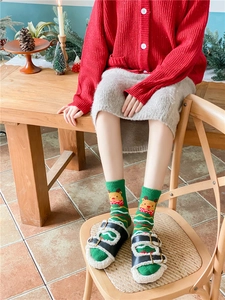 Cozy green Christmas crew socks with reindeer pattern and plush slippers in festive scene